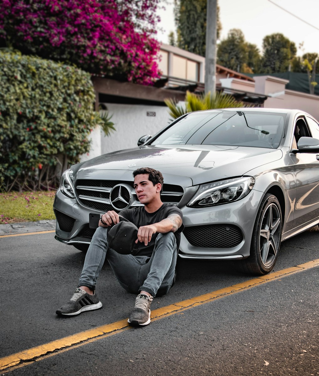 guy with personal auto insurance sitting  beside silver Mercedes-Benz car outdoors